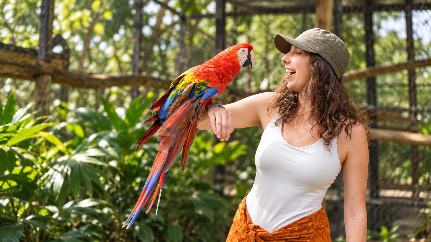 Smiling visitor holding a scarlet macaw at Jungla de Panama